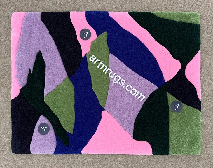 Blue, pink and green leaf rug laid on grey carpet.