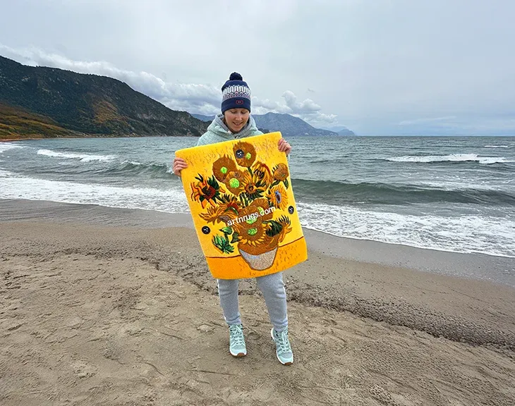 Person holding the Van Gogh Sunflowers wall rug on an overcast beach.