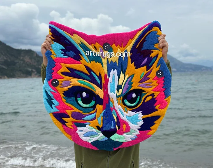 Close-up of the multicolor cat portrait rug beside the water.
