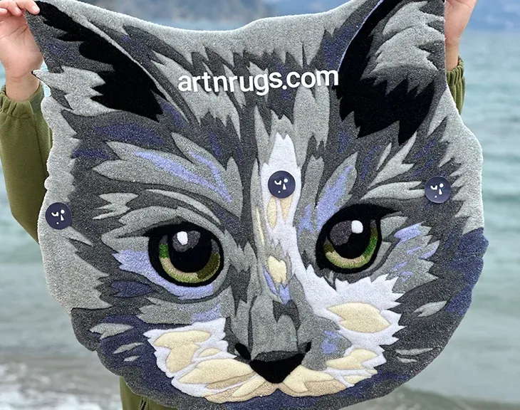 Close-up of the gray cat portrait rug beside the water.