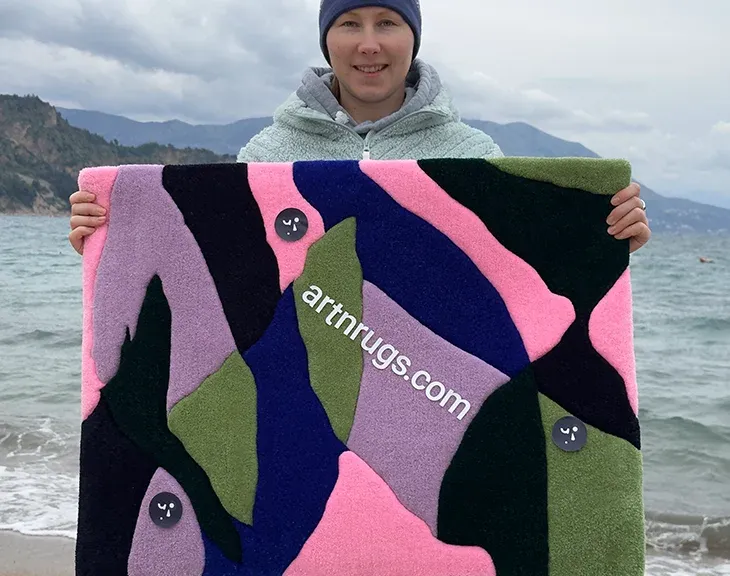 Person holding the abstract leaf rug on an overcast beach.