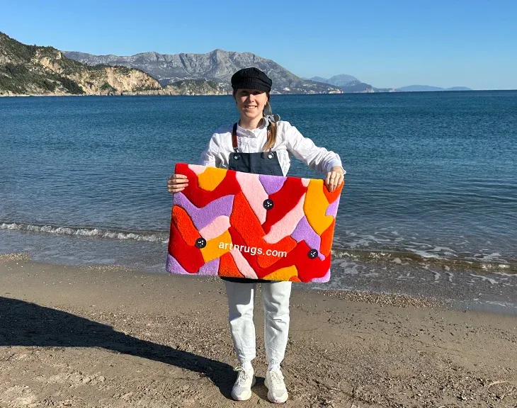 Person holding the parquet wall rug with sea and mountains behind.