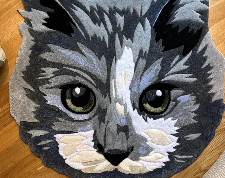 Primer plano de la alfombra retrato de la gata gris sobre un suelo de madera.