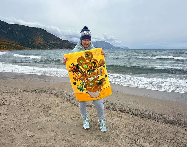 Person hält Van Gogh Sonnenblumen-Wandteppich am Strand bei bewölktem Himmel
